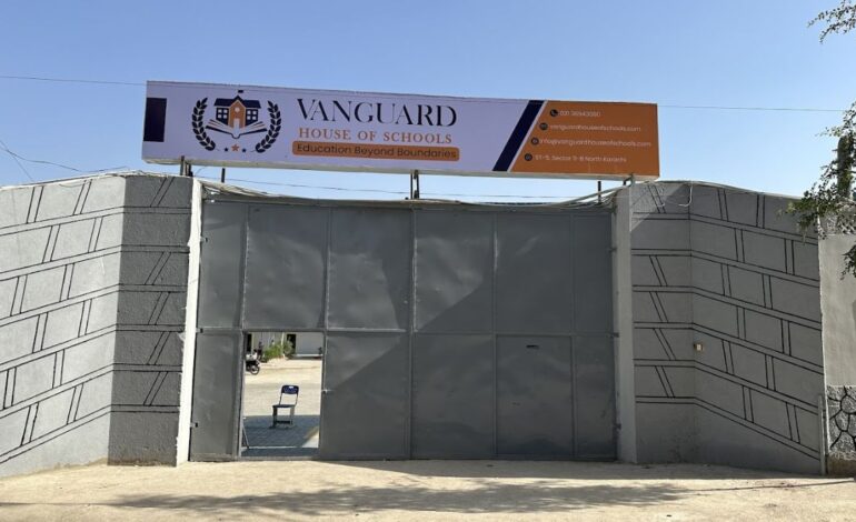 Entrance gate to "Vanguard House of Schools" with a banner above.